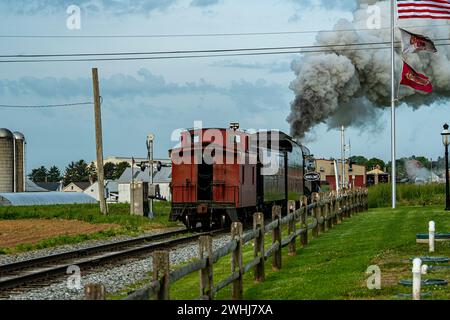 Blick von hinten auf eine moderne Dampflokomotive und Caboose, der Rauch bläst Stockfoto