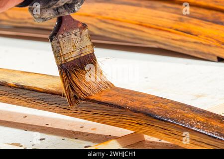 Hand von Handyman lackiert das Holz. Konzept der Heimwerkerarbeiten, Zimmerei-Details mit Holzarbeiten. Stockfoto