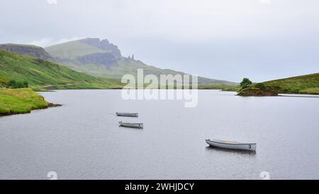 3 weiße Fischerboote auf dem See Loch Leathan an einem nebligen Morgen, Old man of Storr Felsen in der Ferne, Isle of Skye, Schottland, Großbritannien, Europa Stockfoto