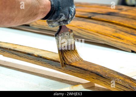 Hand von Handyman lackiert das Holz. Konzept der Heimwerkerarbeiten, Zimmerei-Details mit Holzarbeiten. Painte Stockfoto