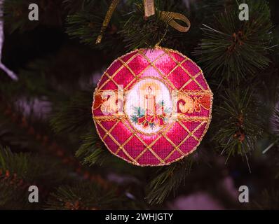 Ein kreuzgenähtes zeitloses Weihnachtsschmuck auf einem Weihnachtsbaum. Dieses rote Weihnachtsschmuck mit Kerze bestickt und von mir gemacht. Stockfoto