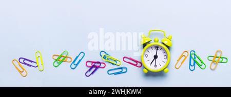 Schulbedarf und Wecker auf blauem Hintergrund Stockfoto