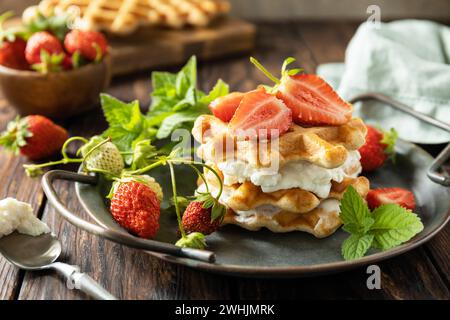 Hausgemachte belgische Waffeln mit frischen Berrie-Erdbeeren und Ricotta-Käse zum Frühstück auf einem rustikalen Tisch. Stockfoto