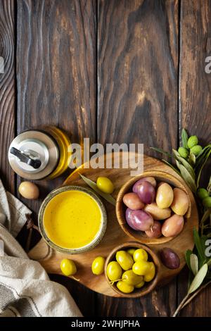 Frisch geerntete Oliven Beeren in Holzschüsseln und gepresstes Öl auf alten Holzbrettern serviert. Blick von oben. Stockfoto
