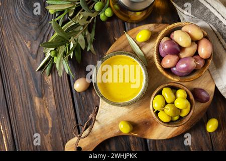Frisch geerntete Oliven Beeren in Holzschüsseln und gepresstes Öl auf alten Holzbrettern serviert. Blick von oben. Stockfoto