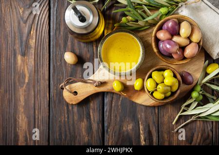 Frisch gepflückte Oliven Beeren in Holzschüsseln und Pressöl auf alten Holzbrettern serviert. Blick von oben. Speicherplatz kopieren. Stockfoto