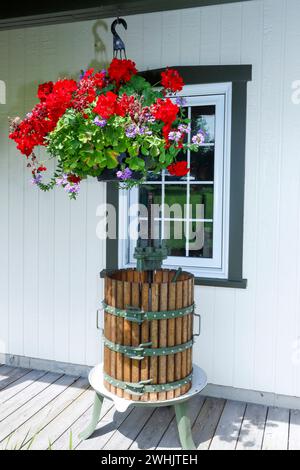 Vintage-Fassade mit Fenster, dekoriert von einem alten Obst- und Traubenbrecher aus Gusseisen und Holz und einer Vase mit hängenden Blumen. Kanada Stockfoto