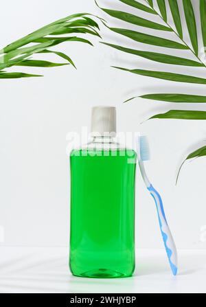 Erfrischende Mundspülung in einer transparenten Plastikflasche und einer Zahnbürste auf weißem Hintergrund Stockfoto