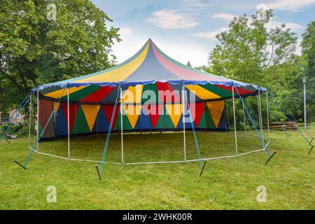 Kleines farbenfrohes Zirkuszelt mit einer Stange, die halb offen auf einer Wiese für eine Sommerparty oder ein Festival steht, Kopierraum Stockfoto