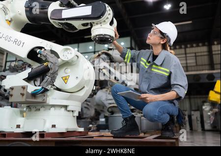 Eine Ingenieurin installiert ein Programm auf einem Roboterarm in einem Roboterlager. Und prüfen Sie die Funktion, bevor Sie die Maschine t senden Stockfoto