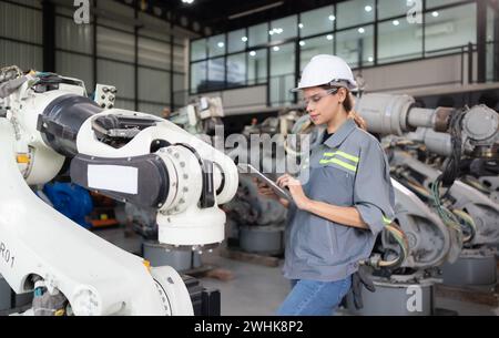 Eine Ingenieurin installiert ein Programm auf einem Roboterarm in einem Roboterlager. Und prüfen Sie die Funktion, bevor Sie die Maschine t senden Stockfoto