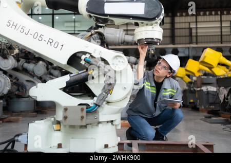 Eine Ingenieurin installiert ein Programm auf einem Roboterarm in einem Roboterlager. Und prüfen Sie die Funktion, bevor Sie die Maschine t senden Stockfoto