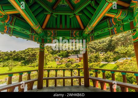Blick auf den künstlichen Teich und das koreanische Gebäude von der Innenseite des Pavillons mit wunderschönen grünen Traditionsmustern in Südkorea Stockfoto