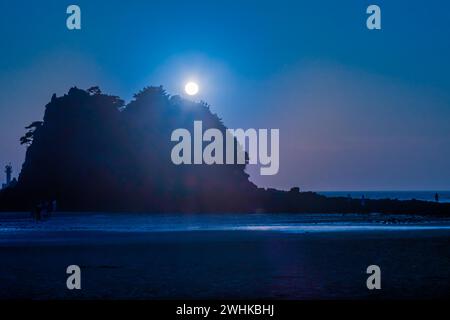 Nicht identifizierbare Touristen auf einer kleinen Insel bei Ebbe mit untergehender Sonne, die blaue Töne in den Himmel in Südkorea wirft Stockfoto