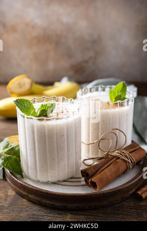 Bananen-Smoothie mit Zimt in Trinkglas auf Holzhintergrund. Entgiftungsmenü. Speicherplatz kopieren. Stockfoto