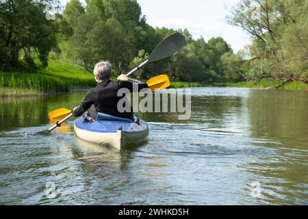 Familien-Kajakausflug für Seigneur und Senora. Ein älteres Ehepaar rudert ein Boot auf dem Fluss, eine Wasserwanderung, ein Sommerabenteuer Stockfoto