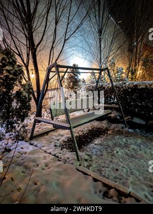 Dicke schneebedeckte hölzerne Schaukelbank im Kaffeegarten Stockfoto