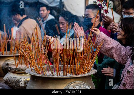 Gläubige beginnen das Jahr des Drachen mit Joss-Stöcken und Gebeten im Wong Tai Sin Tempel. Der Sik Sik Yuen Wong Tai Sin Tempel ist einer der größten taoistischen Tempel in Hongkong und viele Menschen kommen hierher, um die ersten Joss Sticks des neuen Jahres zusammen mit Gebeten für Glück und Gesundheit zu bieten. Stockfoto