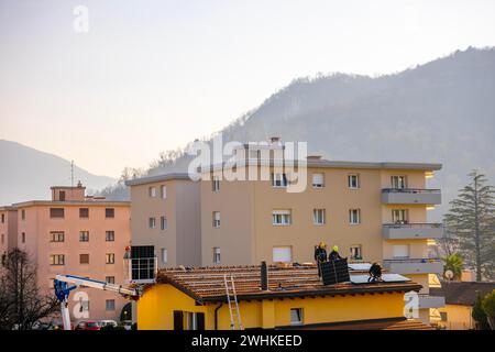 Ingenieure, die Sonnenkollektoren an einem sonnigen Tag in der Schweiz auf dem Dach installieren Stockfoto