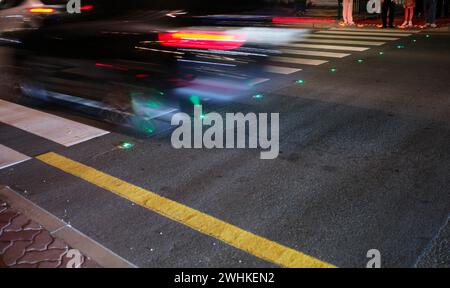Nachtaufnahme, Fußgängerüberquerung, Zebraüberquerung, gegen Smartphone-Junkies, mit Bodenampel, Bodenampel, LED-Leuchten rot und Stockfoto