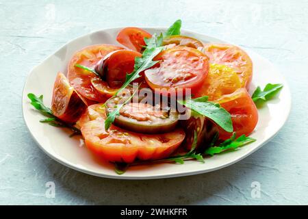 Frische Tomaten und Rucolasalat. Eine Vielzahl von Tomaten verschiedener Art Stockfoto