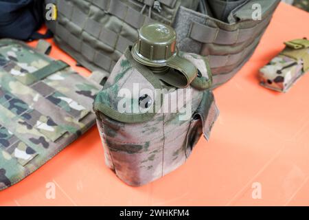 Wasserflasche aus militärischem Kunststoff mit Tarnschutzgewebe. Grüne Militärplastikflasche mit Schutzvorrichtung Stockfoto