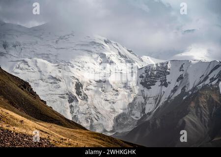 Dramatische Berglandschaft, Bergtal, hinter vergletschtem und schneebedecktem Berggipfel Pik Lenin, Trans Alay Mountains, Pamir Mountains, Osh Stockfoto