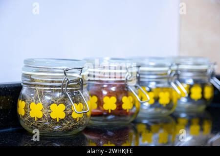 Küchengläser mit Gewürzen und Zutaten auf schwarz-weißem Hintergrund mit Reflexion Stockfoto