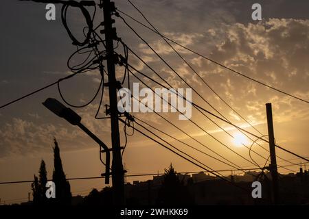 Silhouette von elektrischen Leitungen, Glasfaserkabelknoten und Licht zur goldenen Stunde Stockfoto