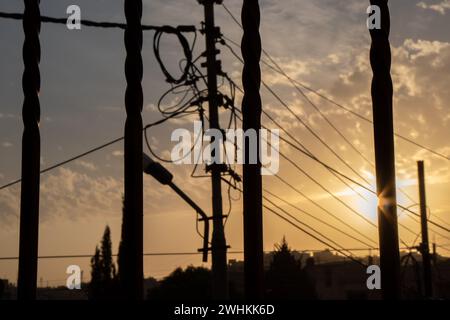 Silhouette von elektrischen Leitungen, Glasfaserkabelknoten und Licht zur goldenen Stunde Stockfoto