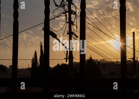 Silhouette von elektrischen Leitungen, Glasfaserkabelknoten und Licht zur goldenen Stunde Stockfoto