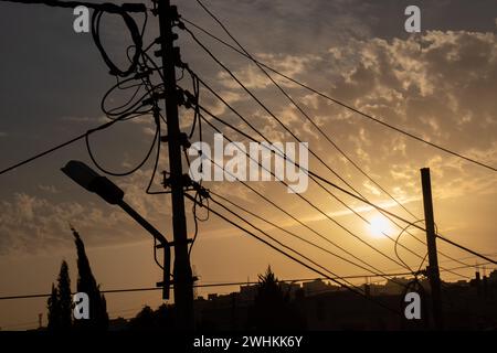 Silhouette von elektrischen Leitungen, Glasfaserkabelknoten und Licht zur goldenen Stunde Stockfoto