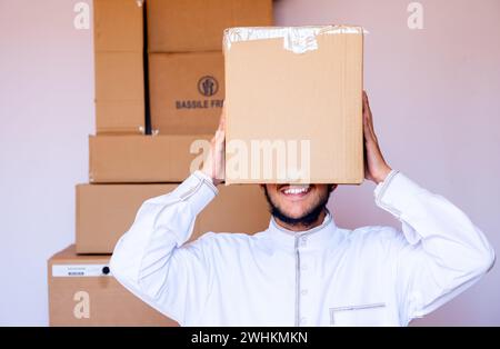 Ein arabischer Mann, der einen Karton auf den Kopf legt Stockfoto