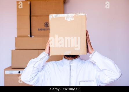 Ein arabischer Mann, der einen Karton auf den Kopf legt Stockfoto