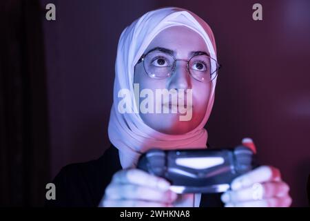 arabisches muslimisches Mädchen, das Konsolenspiele spielt Stockfoto