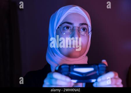 arabisches muslimisches Mädchen, das Konsolenspiele spielt Stockfoto