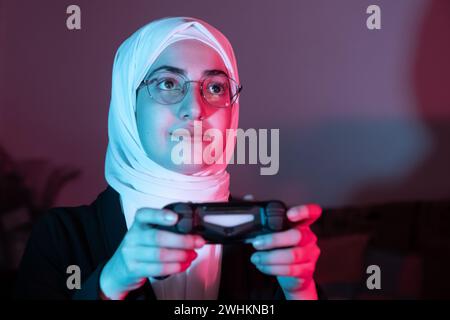 arabisches muslimisches Mädchen, das Konsolenspiele spielt Stockfoto