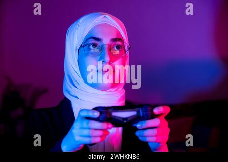 arabisches muslimisches Mädchen, das Konsolenspiele spielt Stockfoto