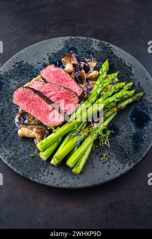 Gourmet Barbecue Dry Aged angus Beef Steak mit grünem Spargel und Pilzen in Trüffelmousse Parfait und wilden Kirschköpfen c Stockfoto