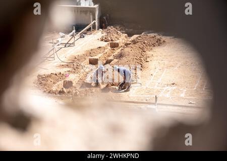 Ein Foto durch ein Loch für einen Arbeiter graben Nach oben die Grundlagen für ein neues Haus nach der Konstruktion in der Nachbarschaft mit Kompressor Stockfoto