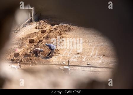 Ein Foto durch ein Loch für einen Arbeiter graben Nach oben die Grundlagen für ein neues Haus nach der Konstruktion in der Nachbarschaft mit Kompressor Stockfoto