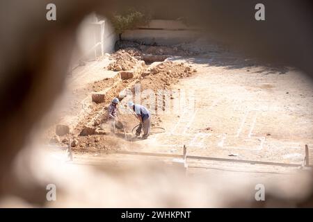 Ein Foto durch ein Loch für einen Arbeiter graben Nach oben die Grundlagen für ein neues Haus nach der Konstruktion in der Nachbarschaft mit Kompressor Stockfoto