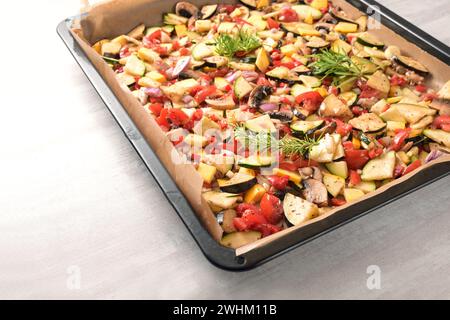 Backofen Gemüse auf einem Blech mit Zucchini, Paprika, Auberginen, Tomaten und Rosmarin garnieren, gesunde vegetarische Mahlzeit für Stockfoto