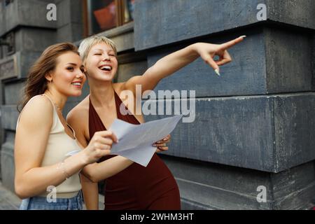 Glückliche junge Touristen-Reisende mit Papierkarte erkunden die neue Stadt. Stockfoto