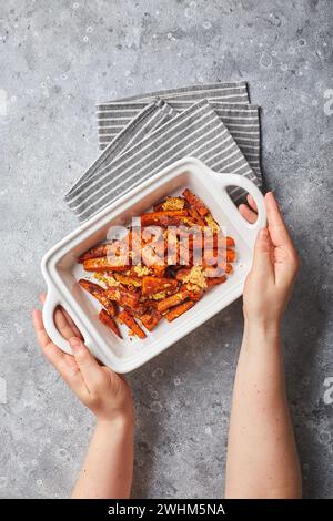 Süßkartoffel mit Käse in Schüssel auf grauem Hintergrund hinterlegt Stockfoto