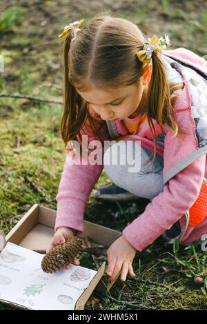Schnitzeljagd für ein Kind im Park. Mädchen, die etwas über die Umwelt lernen. Naturerziehungsaktivität für den Welt-Erde-Tag. Im Frühling auf Entdeckungsreise. Stockfoto