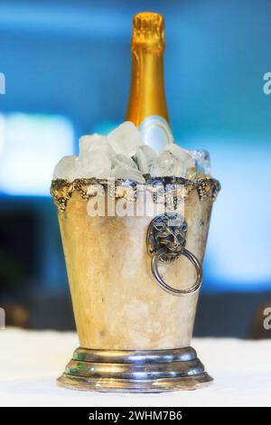 Flasche Weißschaum im Eiskübel auf weißem Tischtuch - fest- und Stilleben. Stockfoto