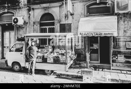 Grüner Lebensmittelhändler mit seinem Truck auf der Straße, vor dem Laden. Schwarz-weiß-Bild, mit einem Gentleman, Sizilien Stockfoto