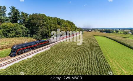 Drohnenansicht eines antiken Dampfeisenzugs, der durch Maisfelder führt Stockfoto