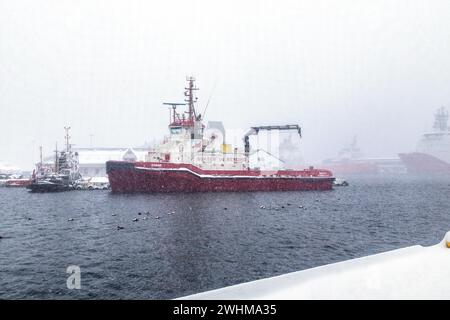 Schlepper Banak mooredin schweren Schnee am Tollboden Kai im Hafen von Bergen, Norwegen. Im Hintergrund ist der alte Schlepper Vulcanus Stockfoto